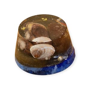 Orgonita en forma de medio cono sobre fondo claro y neutro Detalle de los minerales y espirales dentro de la orgonita medio cono Orgonita medio cono colocada en altar con cristales y velas Pieza de orgonita artesanal proyectando energía en espacio místico Orgonita medio cono como decoración espiritual sobre mesa de meditación