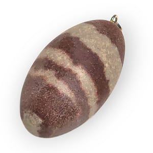 Colgante de piedra Shiva Lingam natural, forma ovalada y tonos marrones y grises, sobre fondo neutro